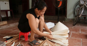 A laidy is working at Chuong conical hat village