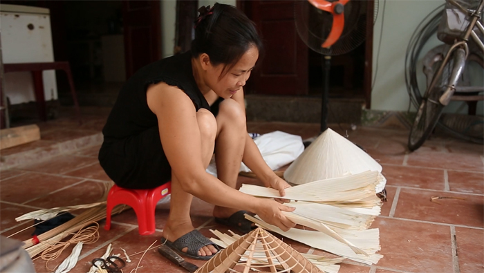 A laidy is working at Chuong conical hat village